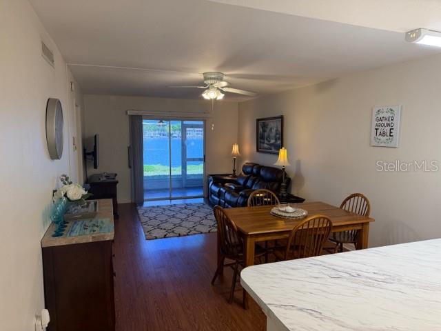 An open-concept living and dining area features wood flooring, a sliding glass door, and furniture — 12538 SW KINGSWAY CIRCLE UNIT 403, LAKE SUZY, FL