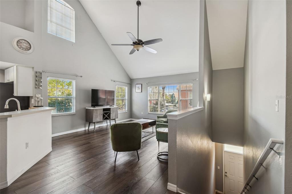 A living room with vaulted ceilings, dark wood flooring, and a staircase leading downstairs — 10462 WHITE LAKE COURT, TAMPA, FL