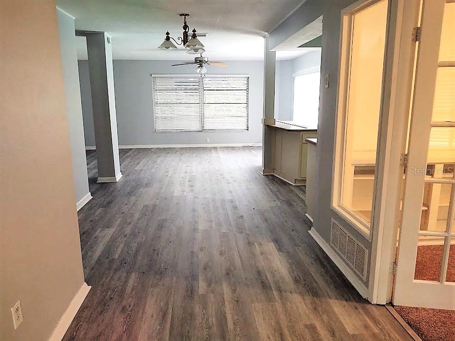A living area with gray wood-look flooring, a ceiling fan, and a kitchen breakfast bar — 11003 66TH TERRACE, SEMINOLE, FL