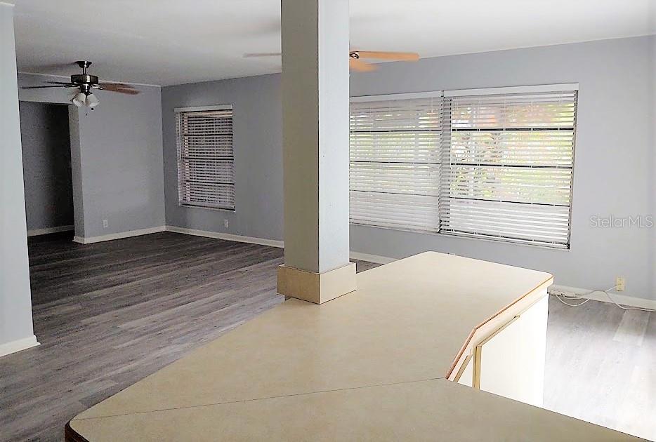 A kitchen counter overlooks a living area with gray walls, wood-look flooring, and ceiling fans — 11003 66TH TERRACE, SEMINOLE, FL