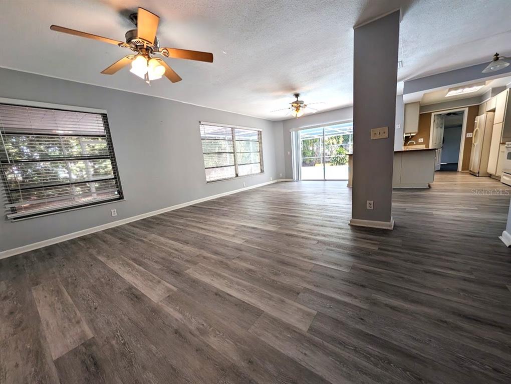 A spacious living room features gray wood-look flooring, two ceiling fans, and large windows — 11003 66TH TERRACE, SEMINOLE, FL