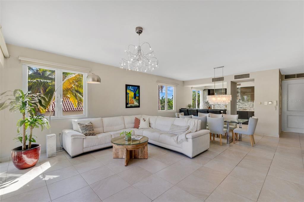 A bright living and dining area features a white sectional sofa, tile floors, and chandeliers — 6690 CALLE TURQUOISE UNIT 324, VEGA ALTA, PR