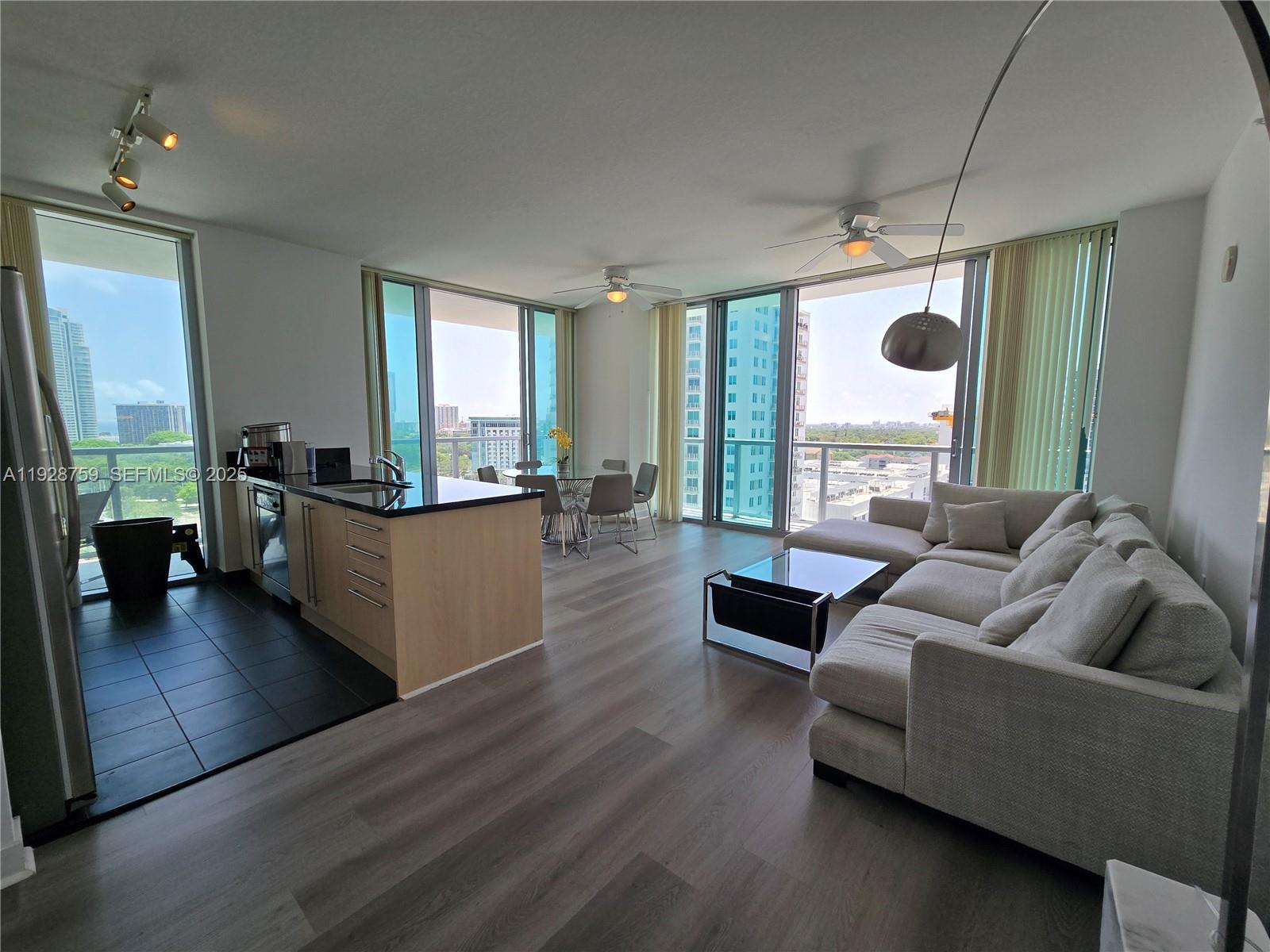An open-concept living area features a kitchen with light wood cabinets and floor-to-ceiling windows — 79 SW 12th St, Miami FL 33130, MIAMI, FL