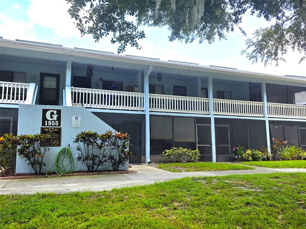 A two-story apartment building exterior features light blue siding, screened porches, and a white railing — 1955 ABRICO DRIVE UNIT G16, LUTZ, FL