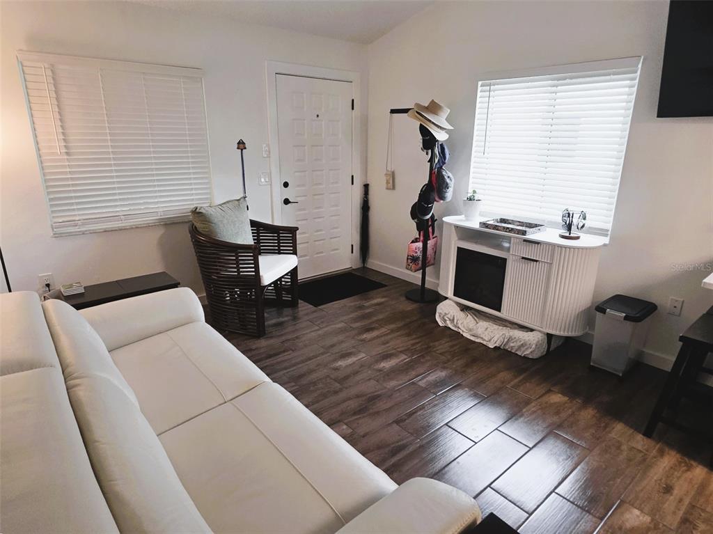 A living room features a white leather sofa, dark wood end tables, and a wicker chair — 1955 ABRICO DRIVE UNIT G16, LUTZ, FL