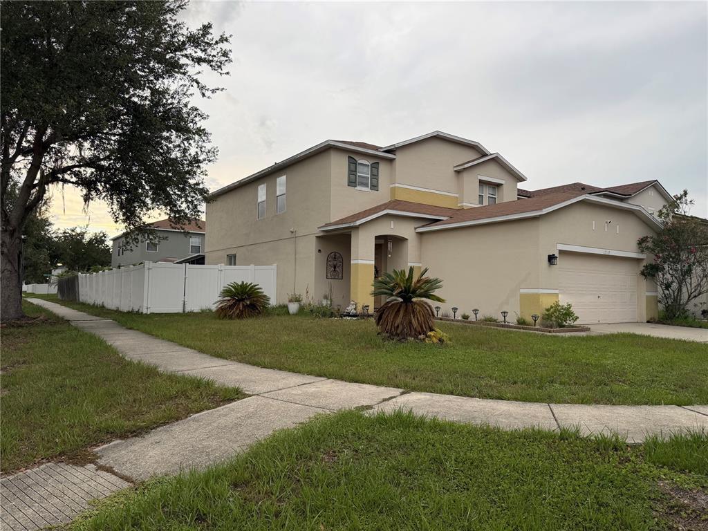 A two-story tan house with a two-car garage and a white vinyl fence — 12139 FOX BLOOM AVENUE, GIBSONTON, FL