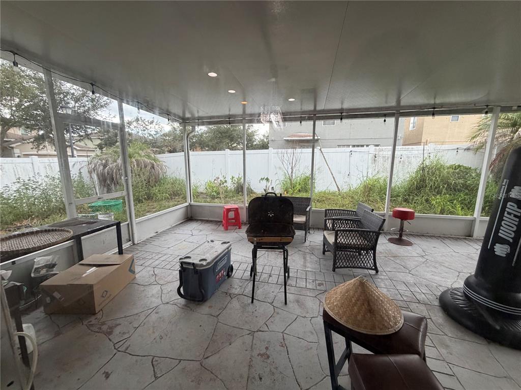 A screened-in patio features a concrete floor, outdoor furniture, a grill, and a backyard view — 12139 FOX BLOOM AVENUE, GIBSONTON, FL