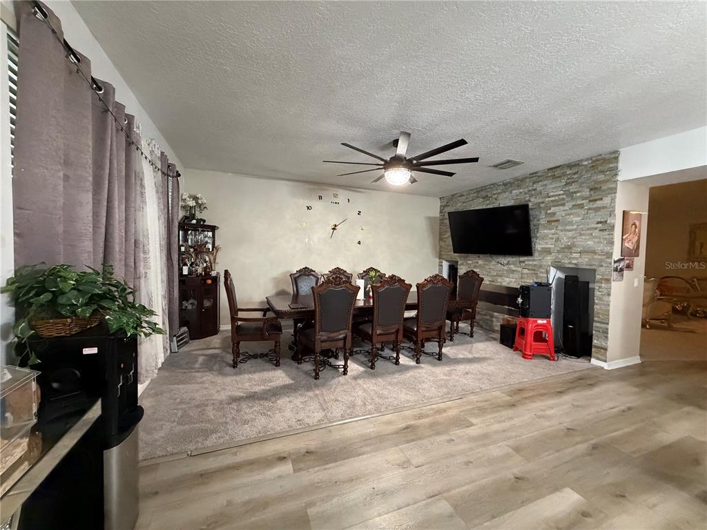 A dining room features a stone accent wall, a large wooden table, and carpeted flooring — 12139 FOX BLOOM AVENUE, GIBSONTON, FL
