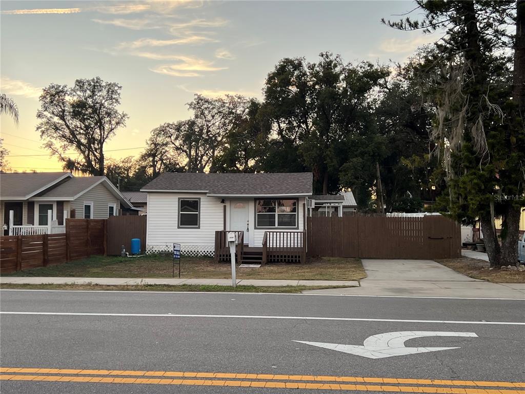 A small, white, single-story house with a wooden deck sits behind a brown privacy fence — 1658 HEMPEL AVENUE, GOTHA, FL