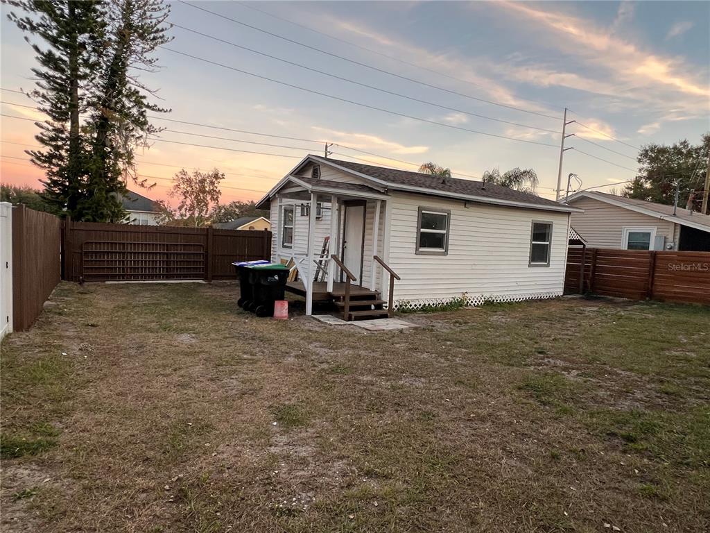 A small, white, single-story house with a front porch sits in a fenced-in yard — 1658 HEMPEL AVENUE, GOTHA, FL