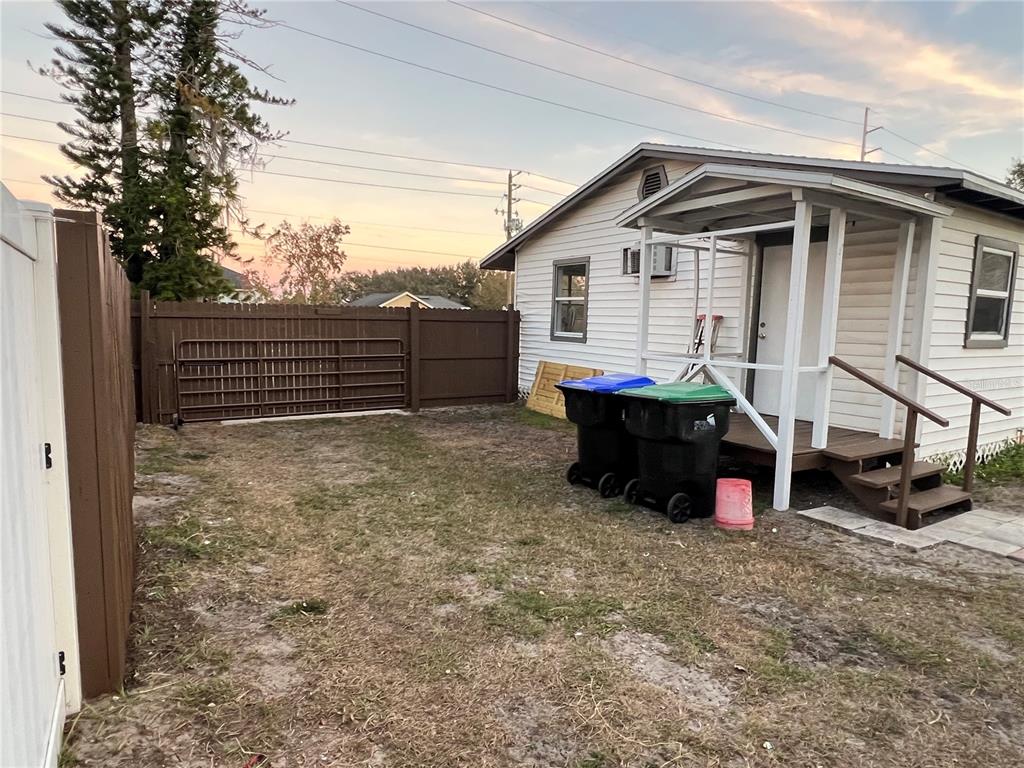 A small white house with a wooden porch sits next to a fenced backyard — 1658 HEMPEL AVENUE, GOTHA, FL