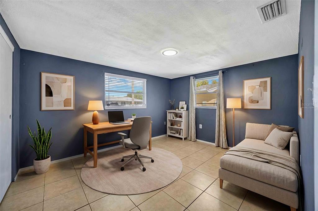 A home office with blue walls, a wooden desk, a chaise lounge, and tile flooring — 9040 LUNAR LANE, PORT RICHEY, FL