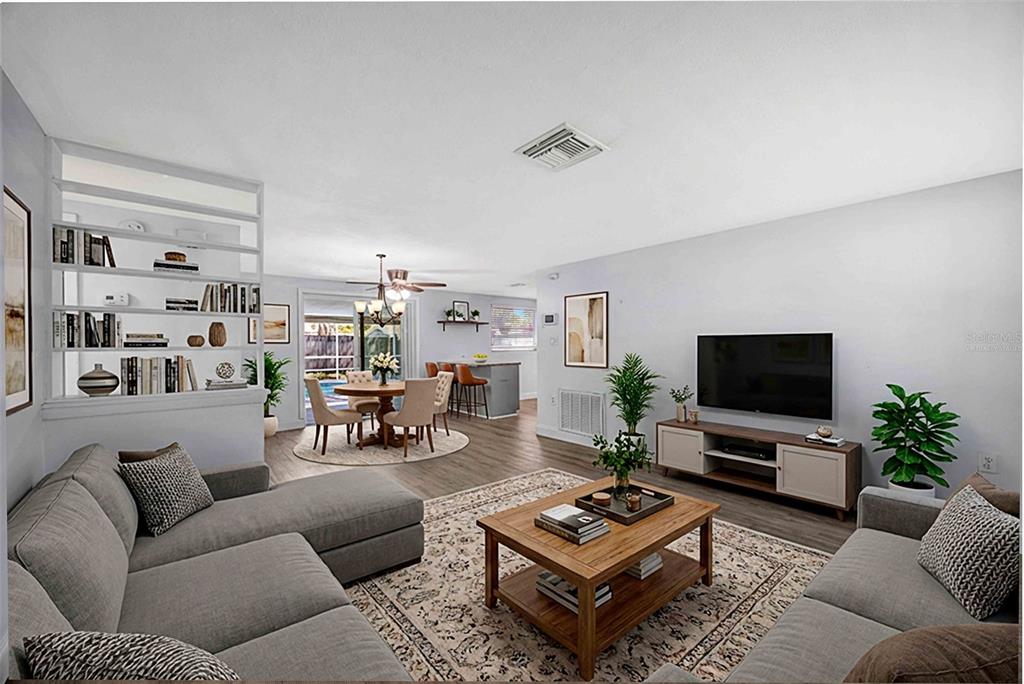 A living room with a sectional sofa, coffee table, and open dining area beyond shelves — 9040 LUNAR LANE, PORT RICHEY, FL