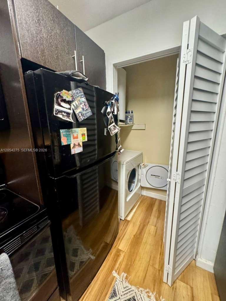 A black refrigerator stands next to a laundry closet containing a white washing machine — 3979 NW 87th Ave # 3979, Sunrise FL 33351, SUNRISE, FL