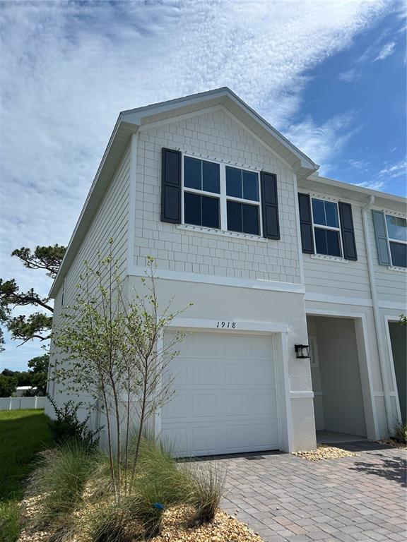 A two-story townhouse exterior features a single-car garage, light siding, and dark window shutters — 1918 KENDALL POINTE PLACE, MELBOURNE, FL