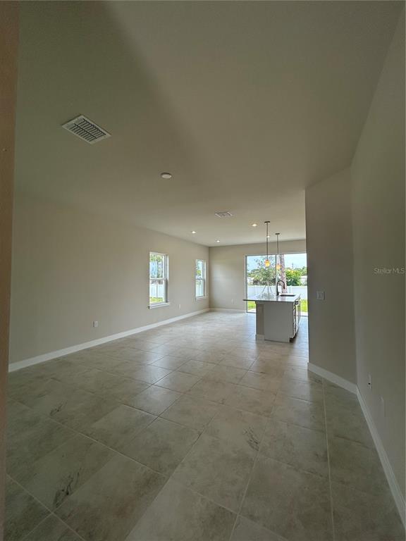 An open-concept living area features light-colored tile flooring, recessed lighting, and a kitchen island — 1918 KENDALL POINTE PLACE, MELBOURNE, FL