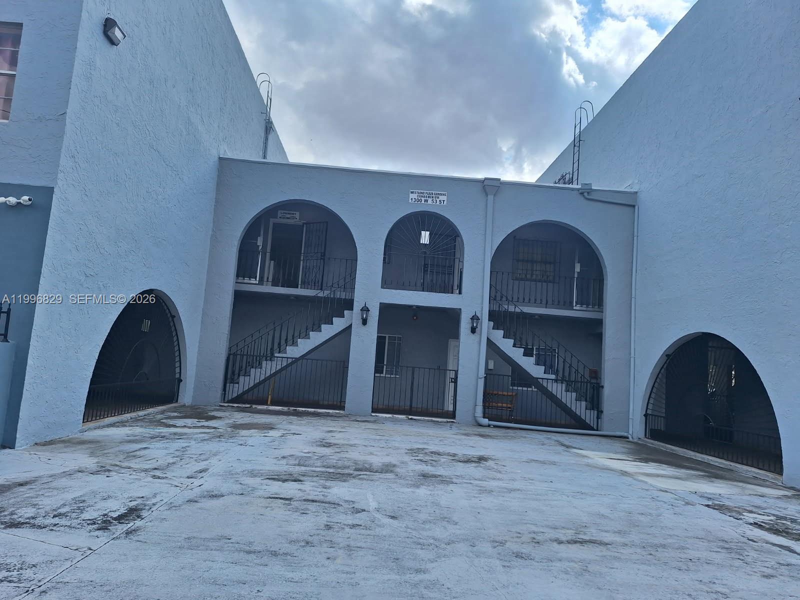 An exterior view of a two-story apartment building with arched entryways and outdoor staircases — 1300 W 53rd St # 35, Hialeah FL 33012, HIALEAH, FL