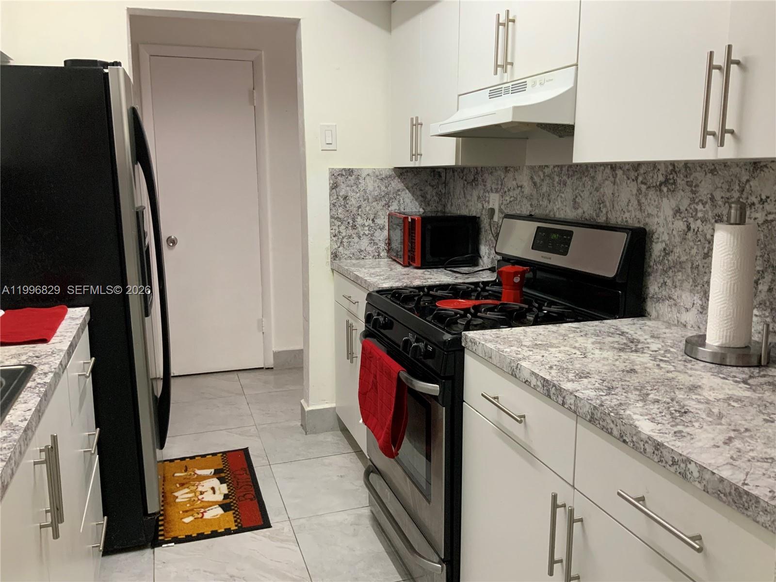 A kitchen features white cabinets, marble-patterned countertops, stainless steel appliances, and gray tile flooring — 1300 W 53rd St # 35, Hialeah FL 33012, HIALEAH, FL