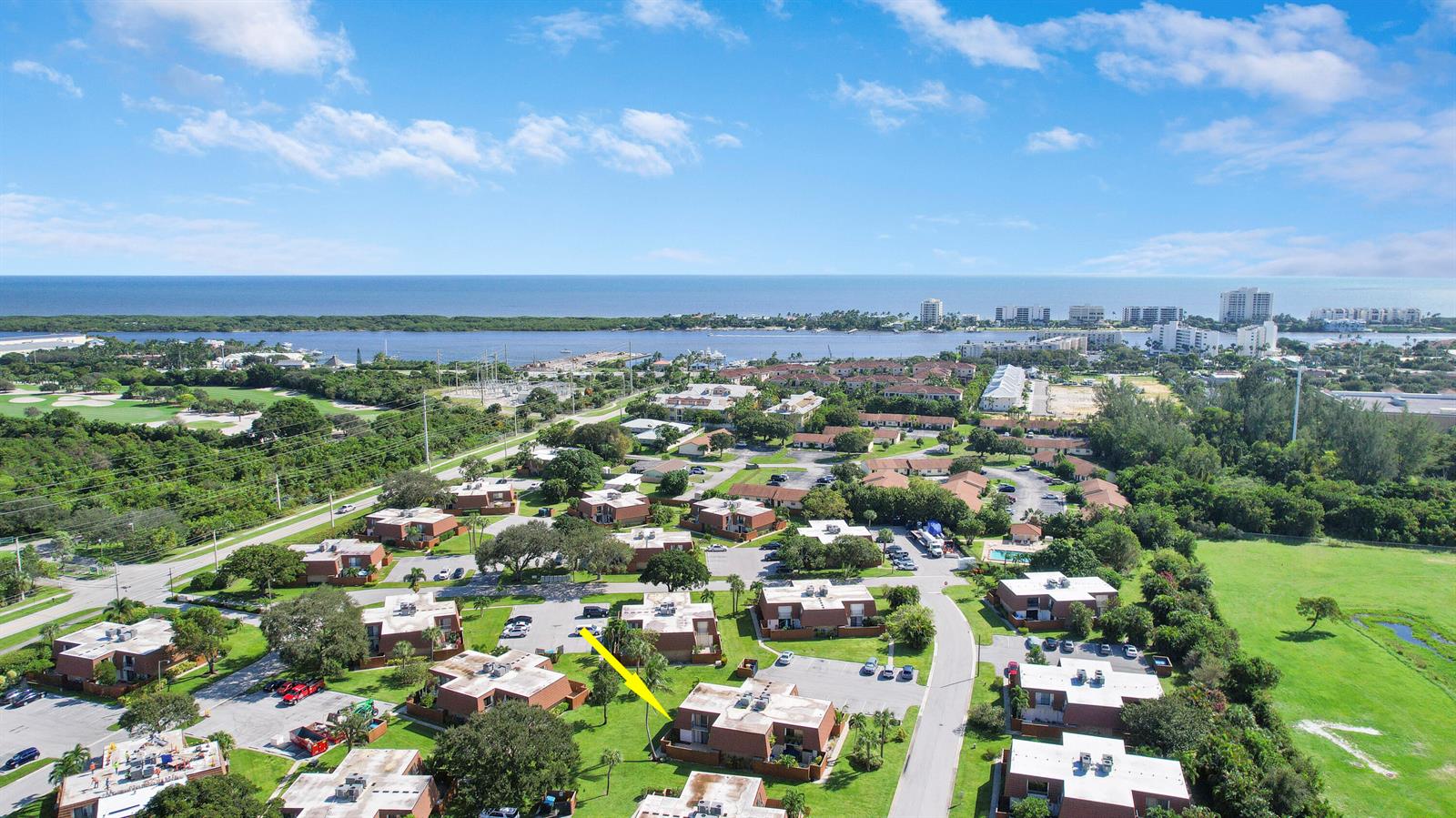 An aerial view shows a residential complex with brown buildings, green lawns, and a distant waterfront — 3900 County Line Road # 21d, Tequesta FL 33469, TEQUESTA, FL