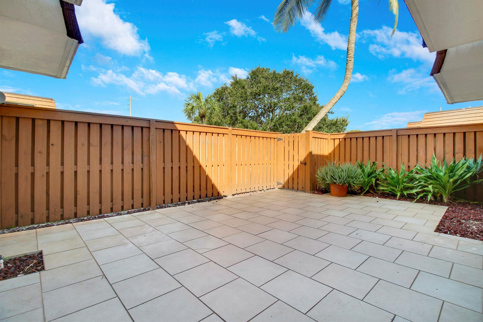 A private patio with light-colored pavers, a wooden privacy fence, and a potted plant — 3900 County Line Road # 21d, Tequesta FL 33469, TEQUESTA, FL