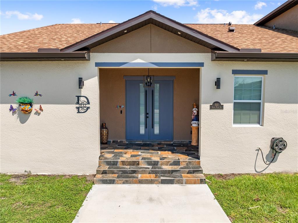 The front exterior of a house features a tiled entryway with double doors and steps — 501 ROYAL PALM DRIVE, KISSIMMEE, FL