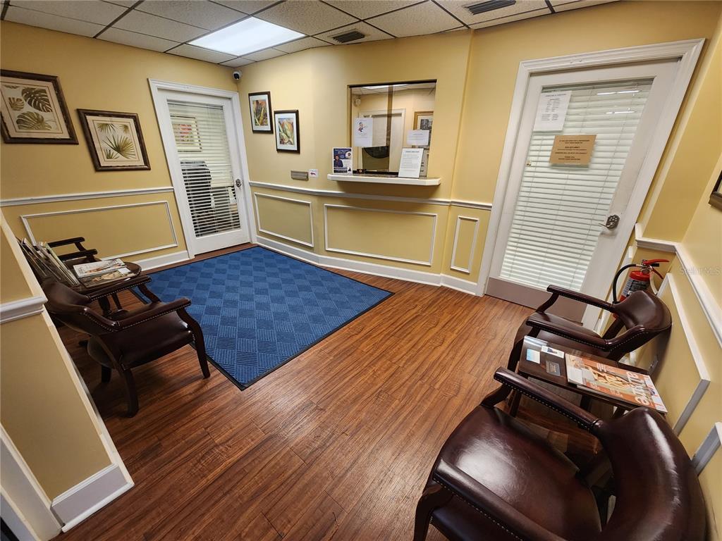 A waiting room with wood-look flooring, a blue area rug, and brown leather chairs — 309 NE 1ST STREET, GAINESVILLE, FL