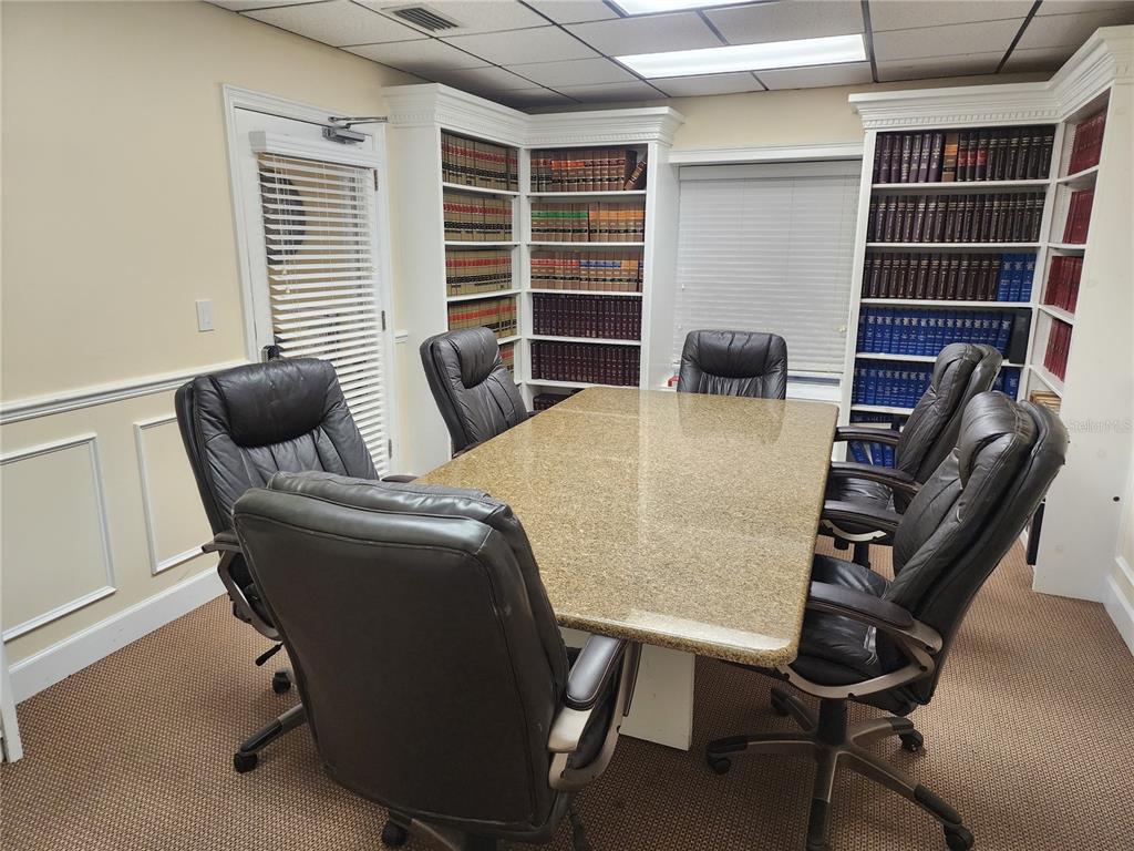 A conference room features a granite table, leather chairs, and built-in bookshelves filled with books — 309 NE 1ST STREET, GAINESVILLE, FL