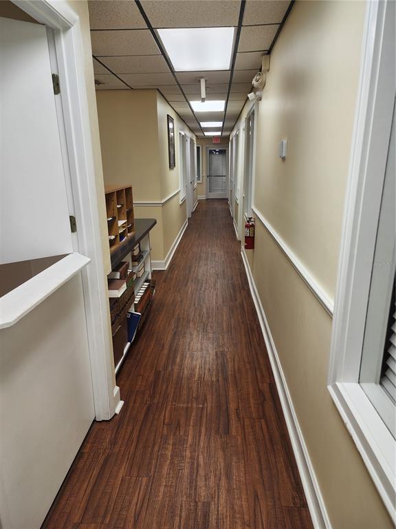A long hallway with wood-look flooring, beige walls, and a drop ceiling with recessed lighting — 309 NE 1ST STREET, GAINESVILLE, FL