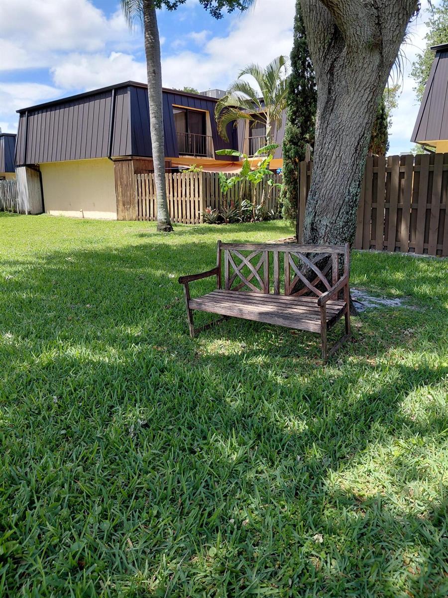 A wooden bench sits on a grassy lawn in front of a multi-story residential building — 2403 S Waterside Drive # 2403, Lake Worth FL 33461, LAKE WORTH, FL