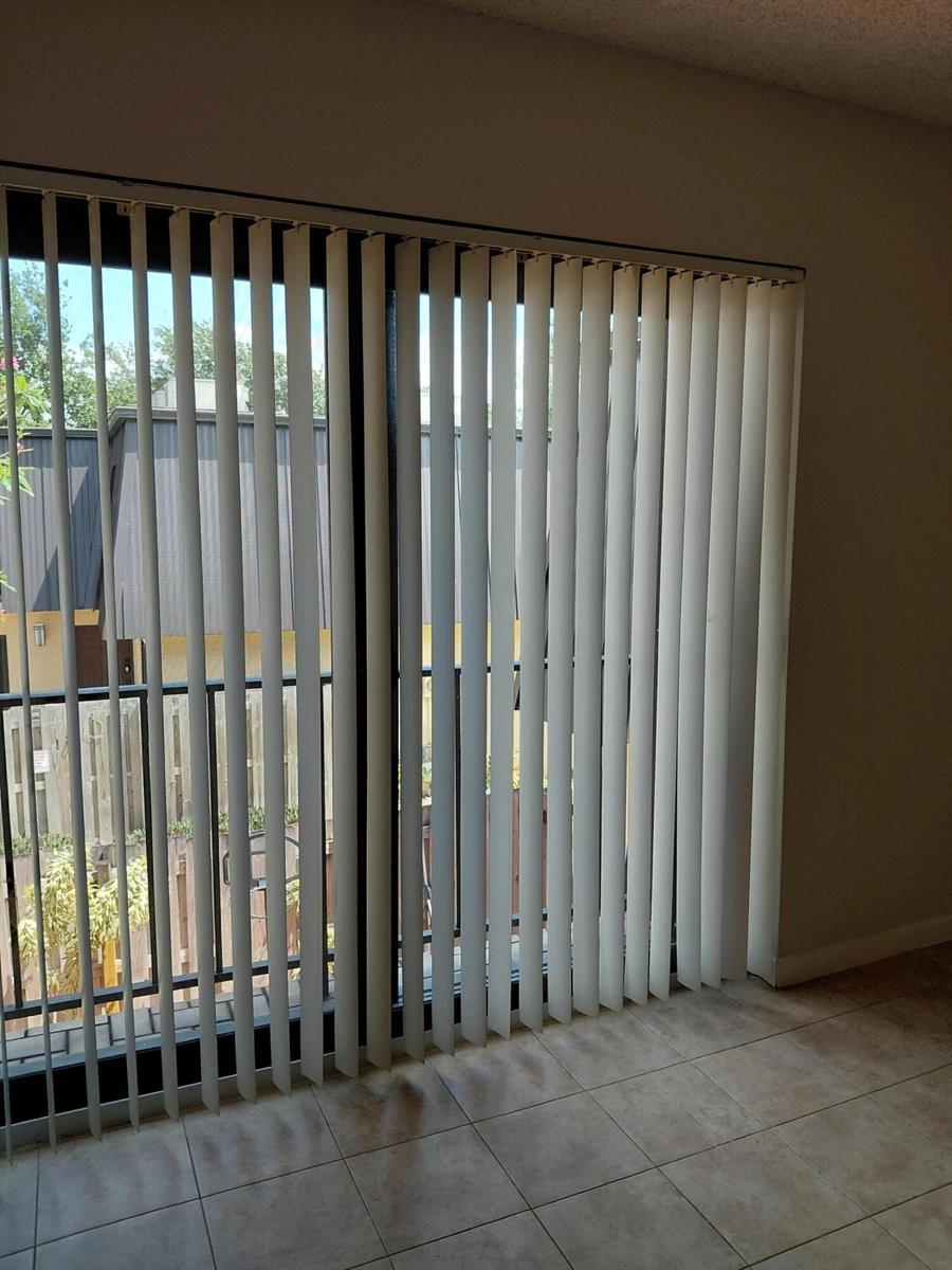A room with tiled flooring features a large sliding glass door covered by vertical blinds — 2403 S Waterside Drive # 2403, Lake Worth FL 33461, LAKE WORTH, FL