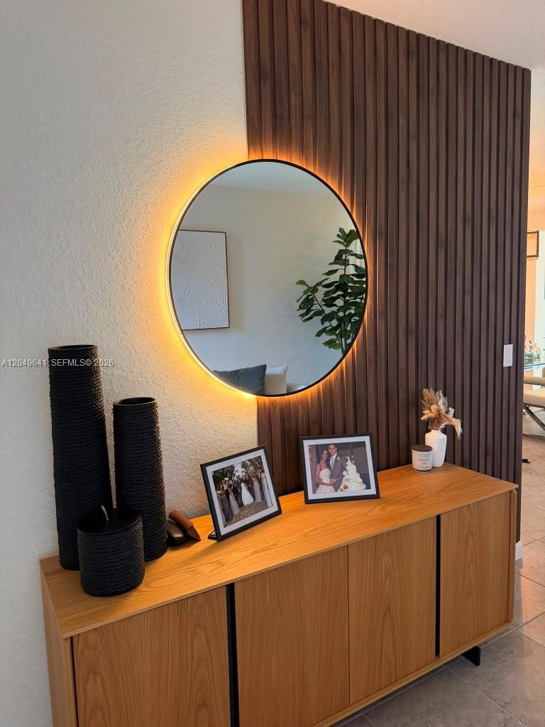A wooden sideboard sits below a backlit circular mirror mounted on a slatted wood wall — 3409 W 104th Ter, Hialeah FL 33018, HIALEAH, FL