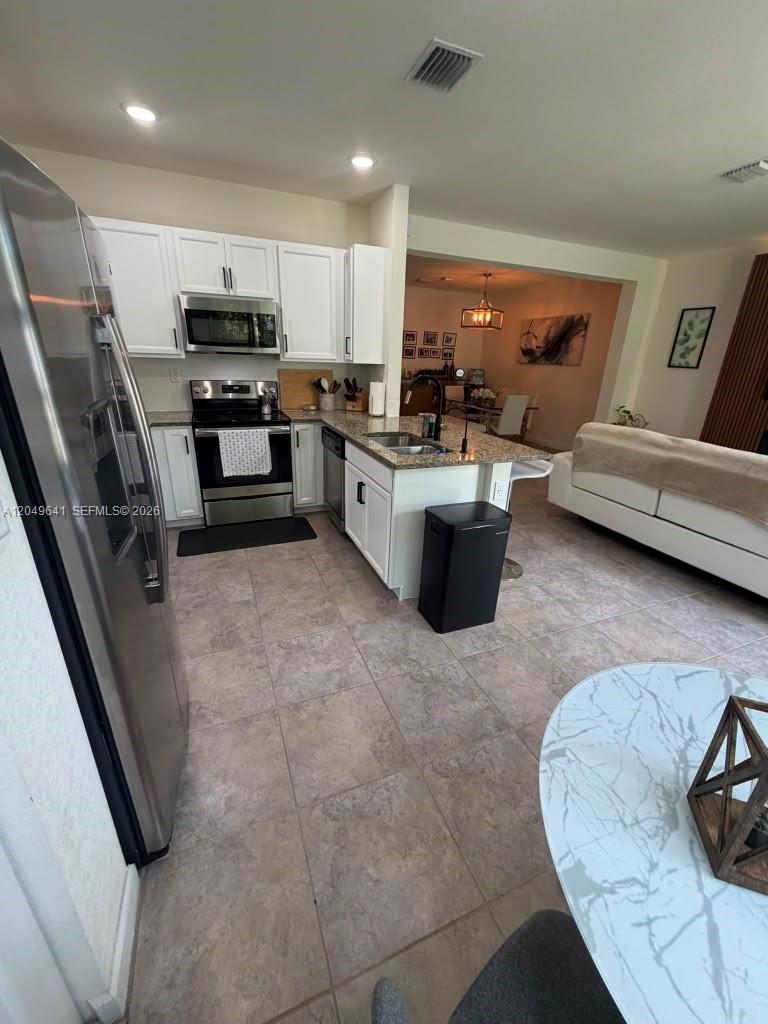 A kitchen with white cabinets, stainless steel appliances, and a granite island countertop — 3409 W 104th Ter, Hialeah FL 33018, HIALEAH, FL