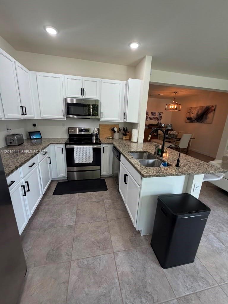 A kitchen features white cabinets, granite countertops, stainless steel appliances, and tile flooring — 3409 W 104th Ter, Hialeah FL 33018, HIALEAH, FL