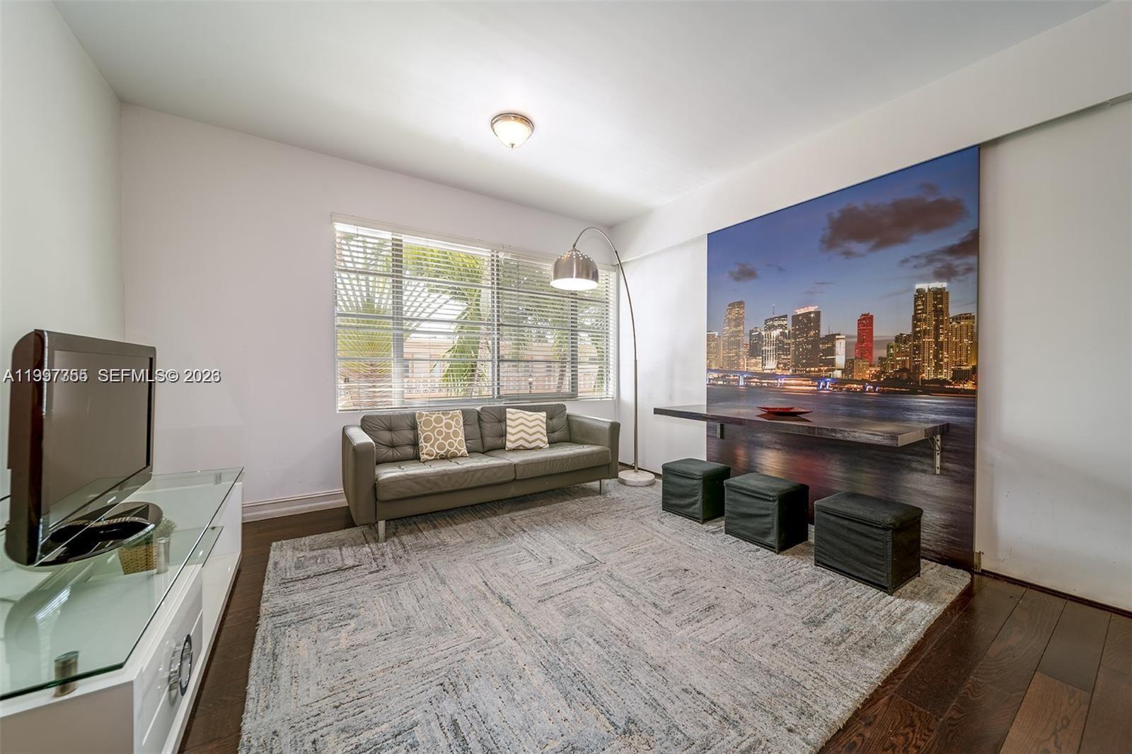 A living room features a gray sofa, a wall-mounted desk, and a large city mural — 601 11th St # 206, Miami Beach FL 33139, MIAMI BEACH, FL