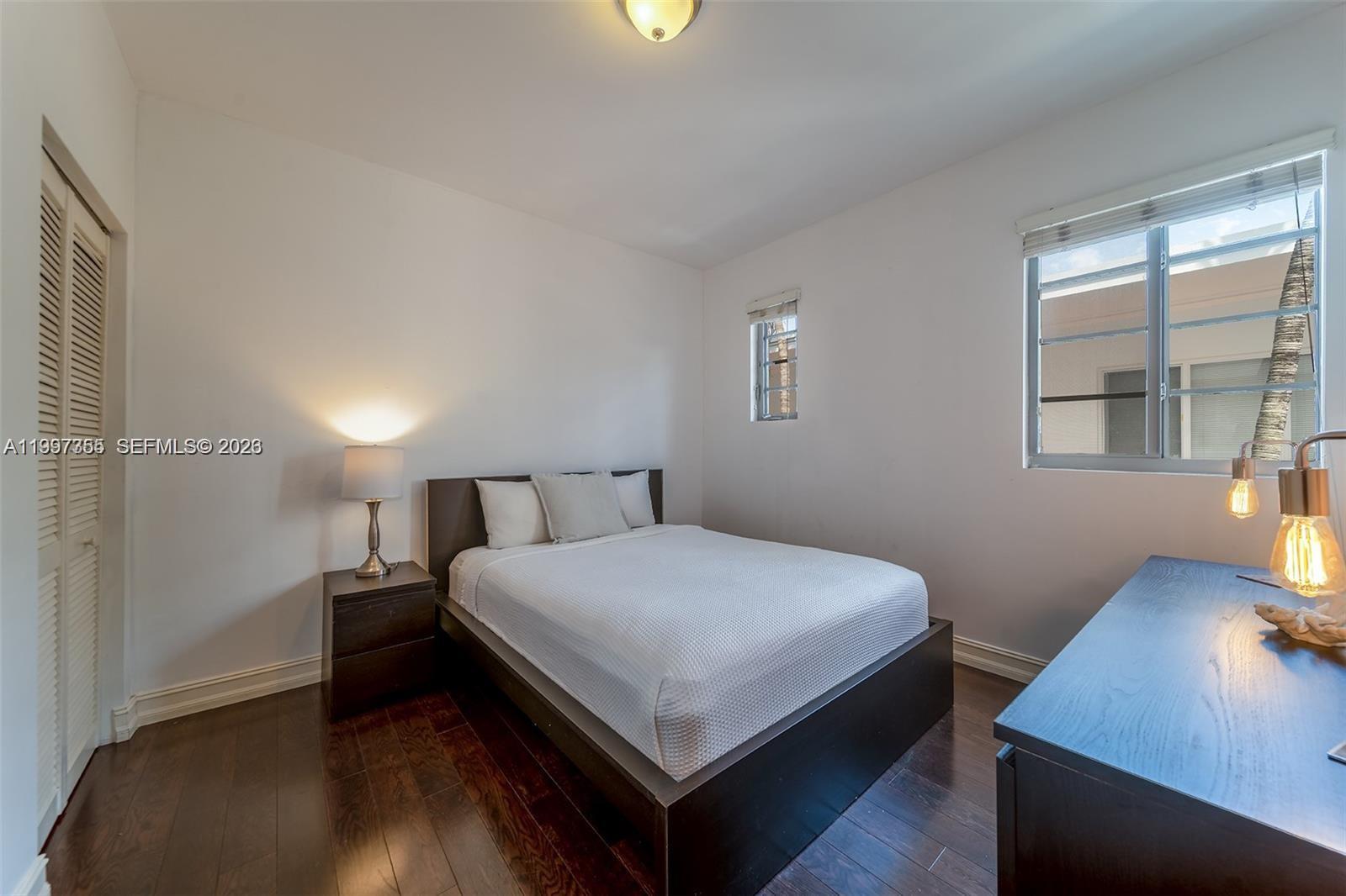 A bedroom features a dark wood bed frame, matching nightstand, and dark hardwood flooring — 601 11th St # 206, Miami Beach FL 33139, MIAMI BEACH, FL