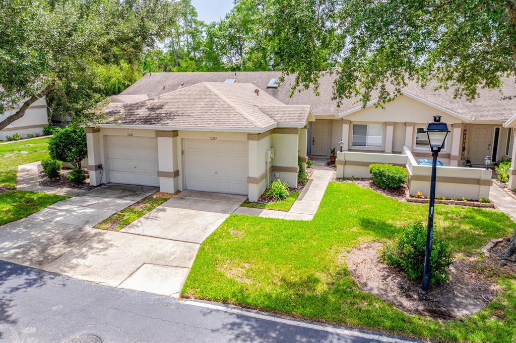 An exterior view of a single-story duplex with two garages and a shared front walkway — 13329 LAVER LANE, ORLANDO, FL