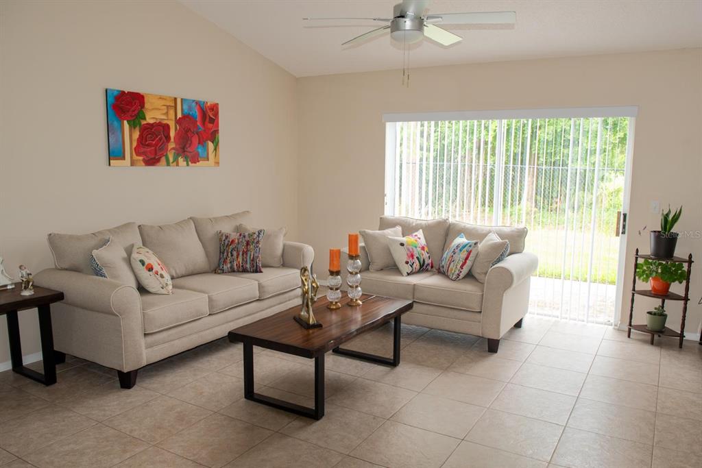 A living room features two beige sofas, a wooden coffee table, and tile flooring — 13329 LAVER LANE, ORLANDO, FL
