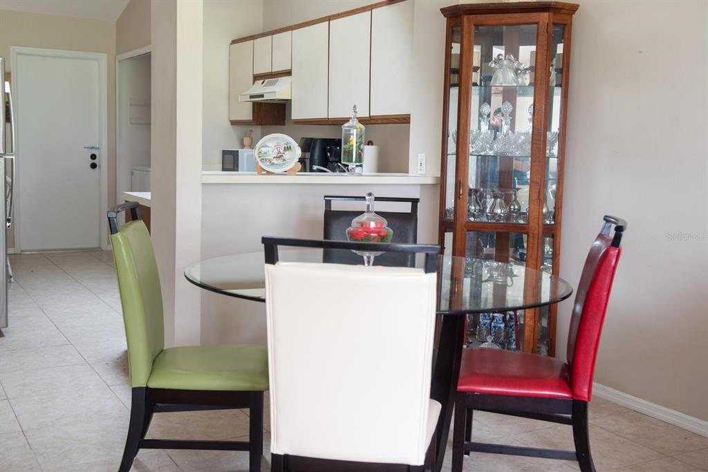 A dining area features a glass-topped table with colorful chairs next to a kitchen counter — 13329 LAVER LANE, ORLANDO, FL