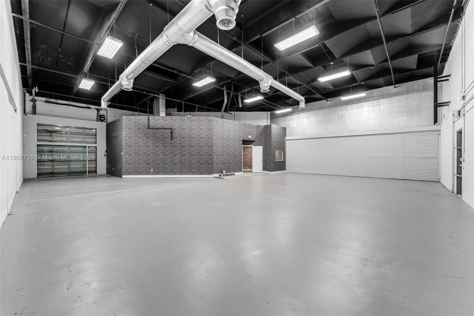 An empty industrial warehouse space features a brick partition wall and exposed ceiling ductwork — 9450 NW 58th St # 3, Doral FL 33178, DORAL, FL