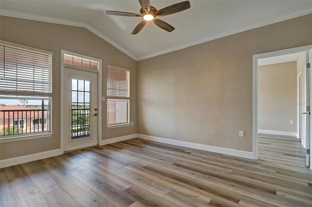 An empty room with wood-look flooring, a ceiling fan, and a door leading to a balcony — 5000 CULBREATH KEY WAY UNIT 4-306, TAMPA, FL