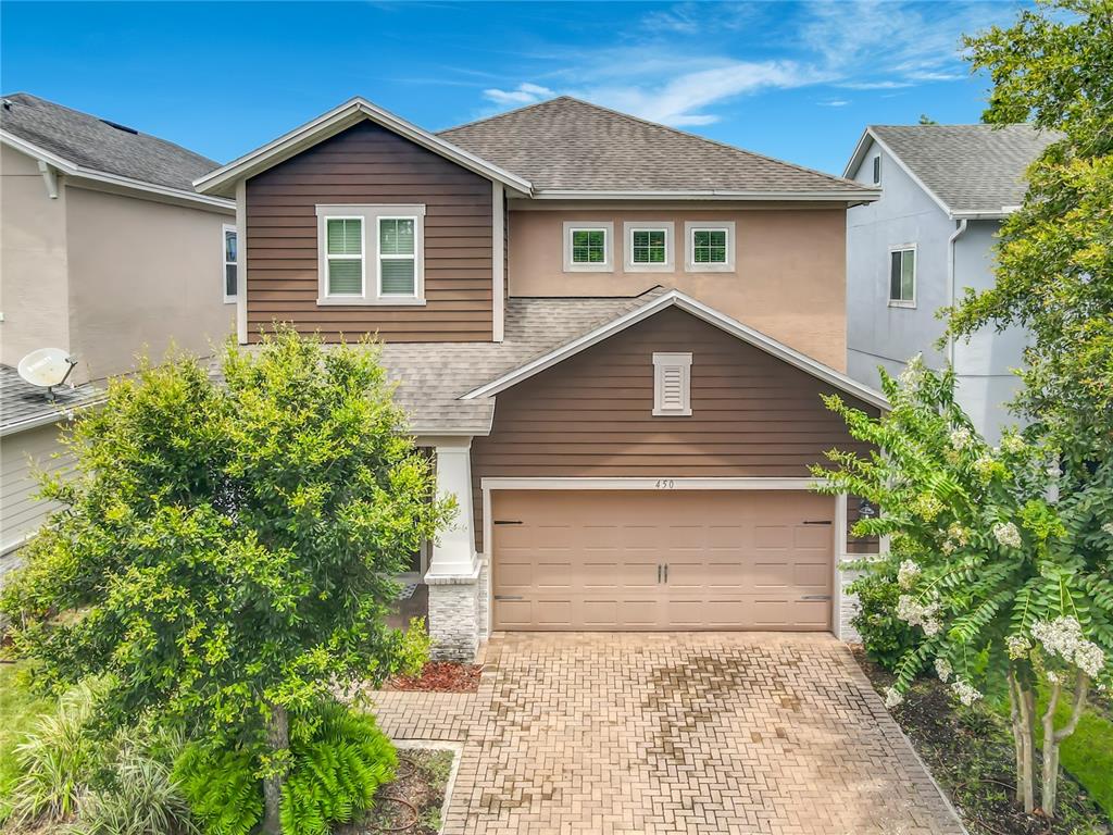 A two-story house with a brown horizontal-siding facade, a two-car garage, and a paver driveway — 450 WINDY PINE WAY, OVIEDO, FL