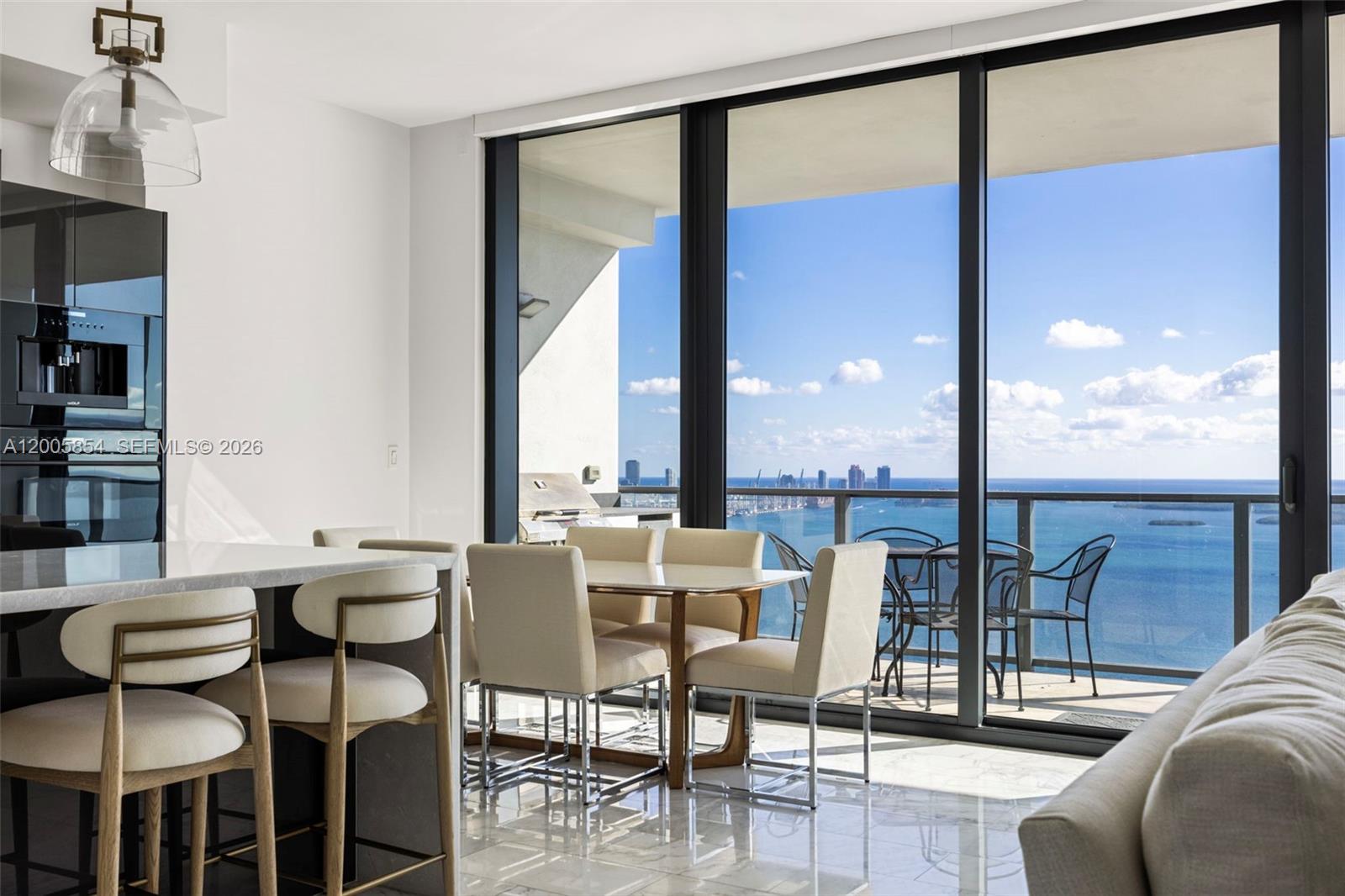 A modern dining area features a glass-topped table, upholstered chairs, and a balcony with ocean views — 1451 Brickell Ave # 4002, Miami FL 33131, MIAMI, FL