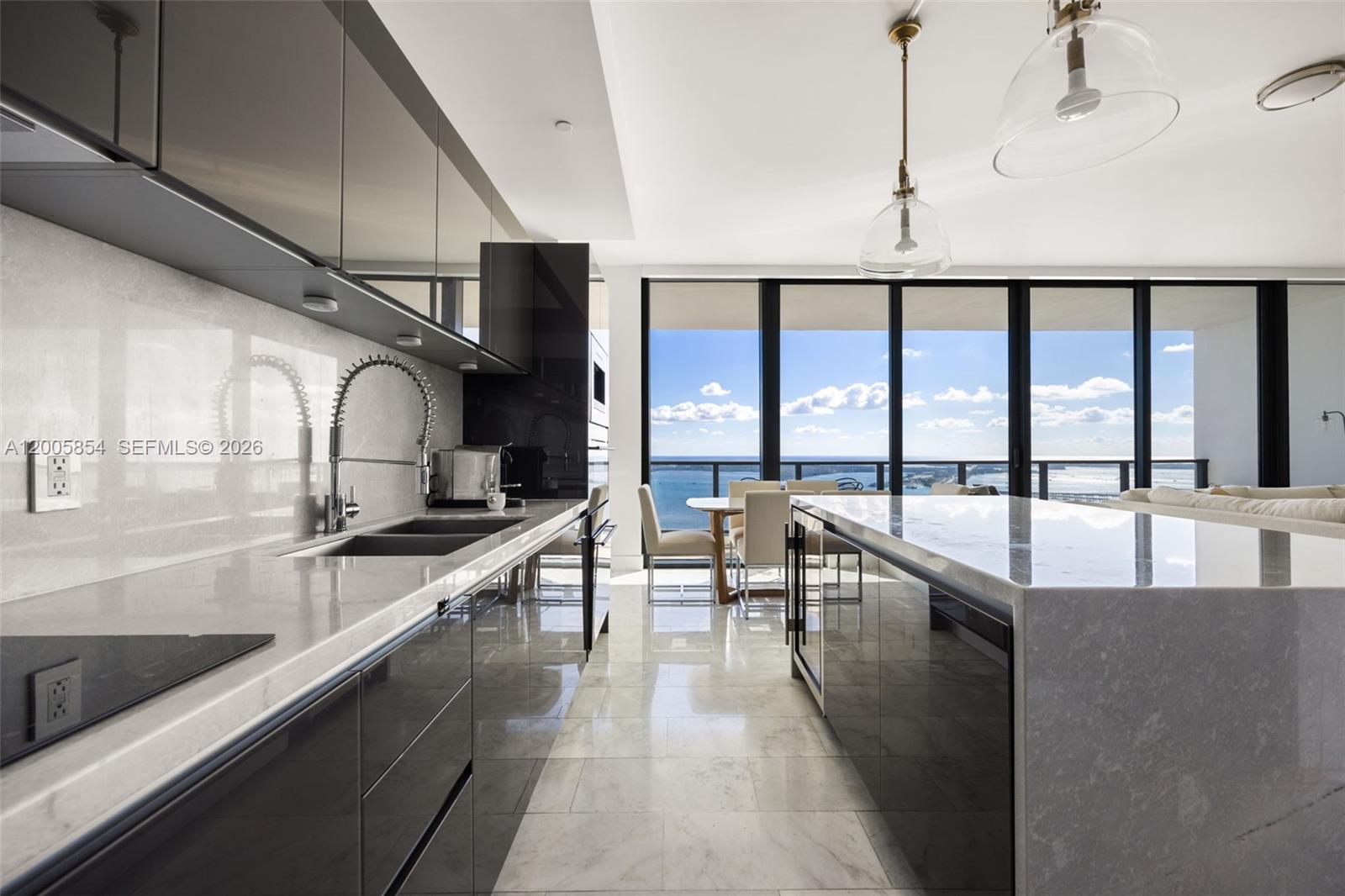 A modern kitchen features dark glossy cabinetry, marble countertops, and floor-to-ceiling windows with ocean views — 1451 Brickell Ave # 4002, Miami FL 33131, MIAMI, FL