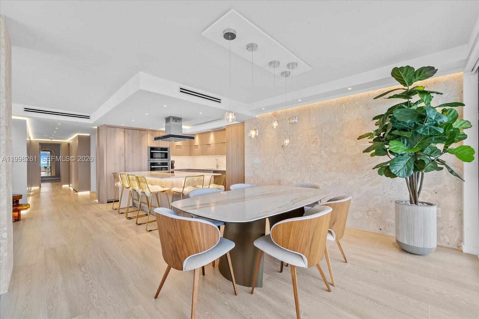A modern dining area and kitchen feature a stone accent wall and light wood flooring — 199 Ocean Lane Dr # 1001, Key Biscayne FL 33149, KEY BISCAYNE, FL