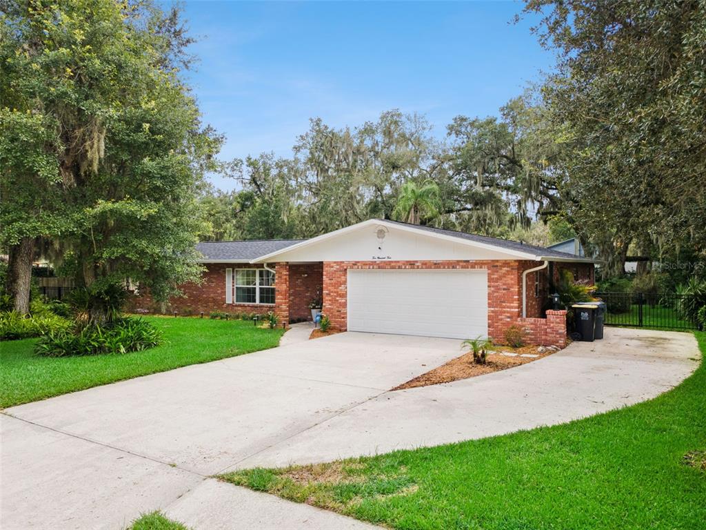 A single-story brick house with a white garage door and a concrete driveway — 204 BIRCH LANE, LAKELAND, FL