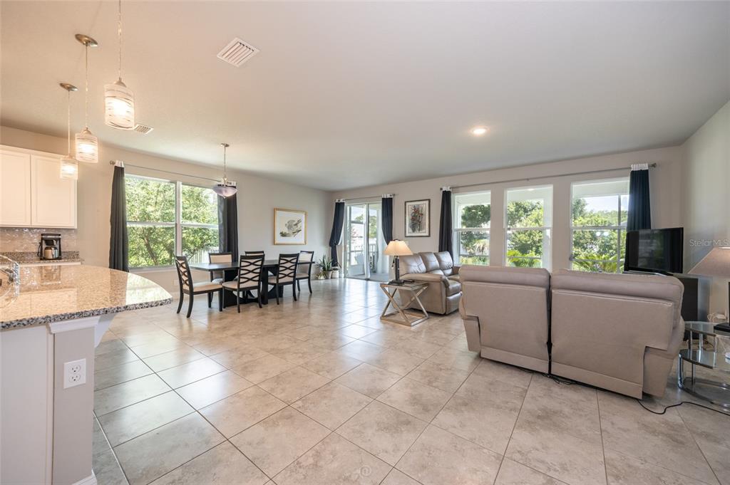 An open-concept living and dining area features tile flooring, neutral walls, and large windows — 3 EASTMAN LANE, PALM COAST, FL