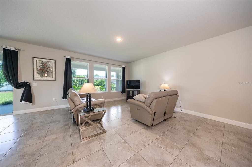 A living room with light tile floors, two beige recliners, and large windows with curtains — 3 EASTMAN LANE, PALM COAST, FL
