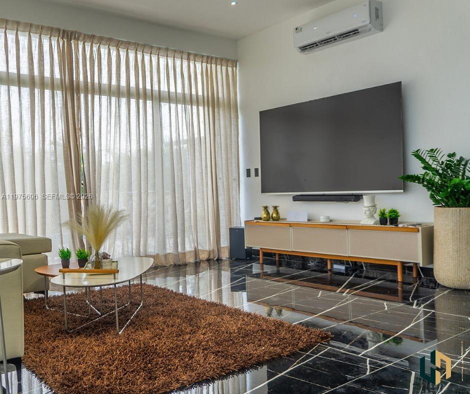 A living room features a large television, a media console, and black marble flooring — Las Canas La Estancia Golf and Country Club, DR, DR