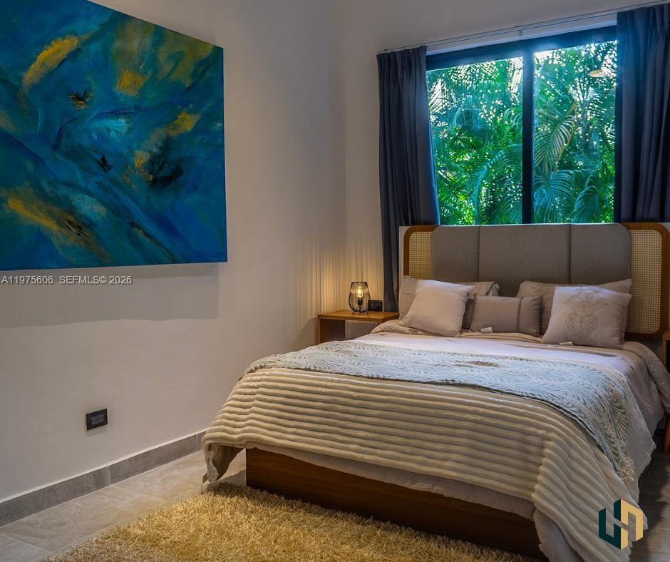 A bedroom features a bed with a cane headboard, a large abstract painting, and window views — Las Canas La Estancia Golf and Country Club, DR, DR