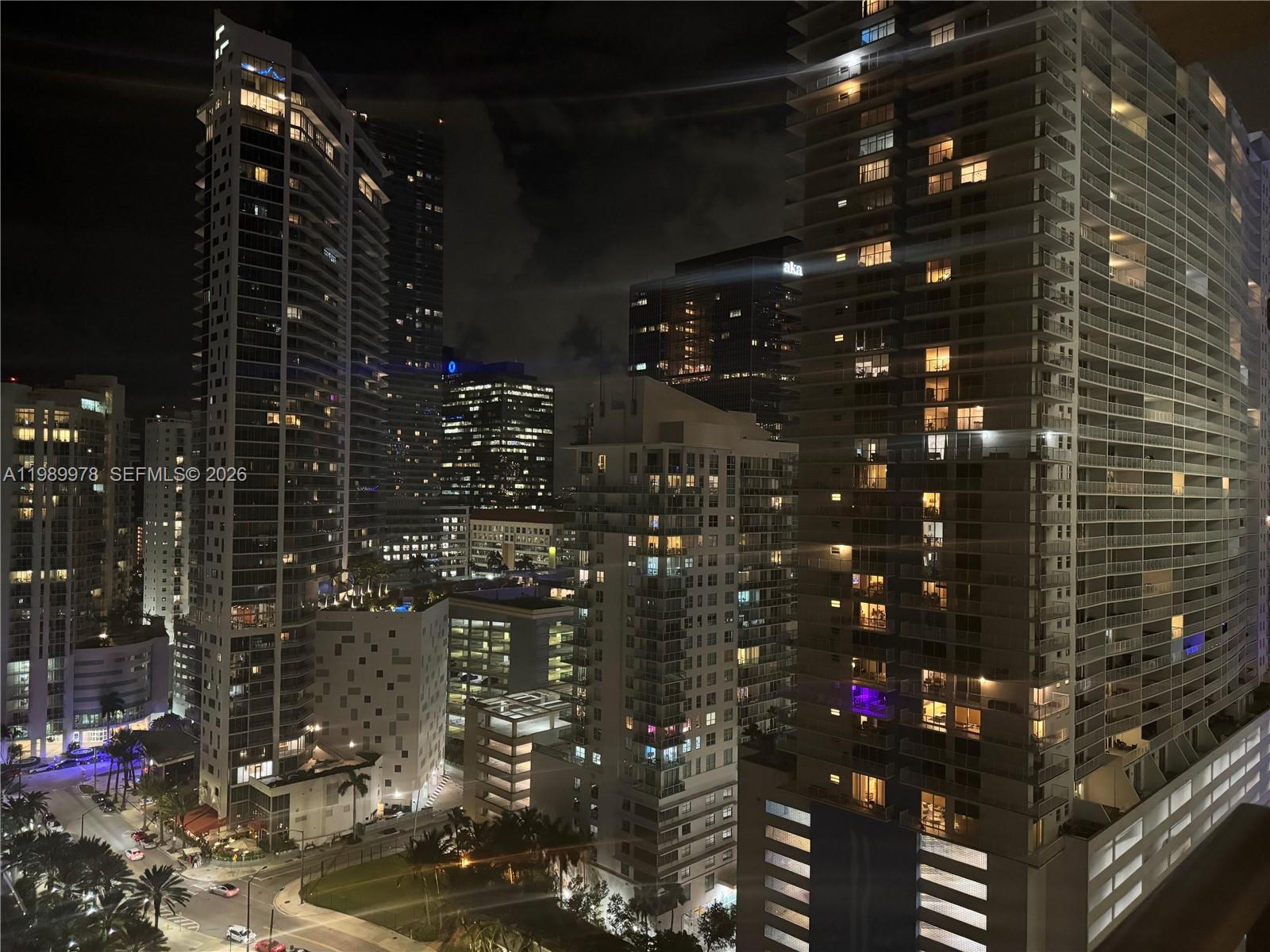 An elevated night view of a dense urban skyline featuring multiple illuminated high-rise apartment buildings — 1155 BRICKELL BAY DR # 2309, Miami FL 33131, MIAMI, FL
